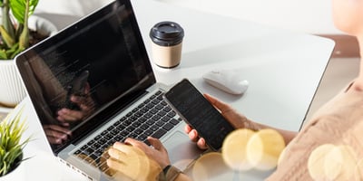 tech working on computer with smartphone